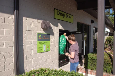 Customer placing a tagged green bag into a BottleDrop secure drop door