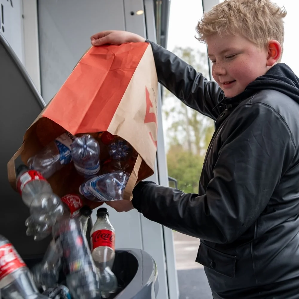 Customer pouring a bag of empty beverage containers into an Envipco QUANTUM bulk-feed machine